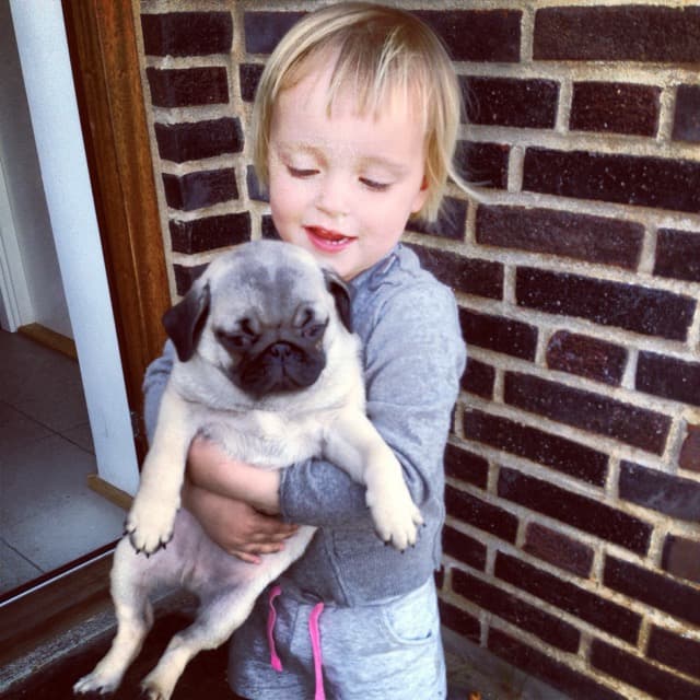 Penelope med en lille mopsehvalp i armene